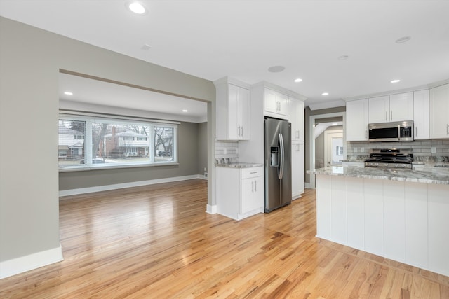 kitchen featuring white cabinetry, light wood-type flooring, light stone countertops, and appliances with stainless steel finishes