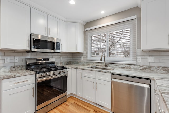 kitchen featuring sink, light stone countertops, white cabinets, and appliances with stainless steel finishes