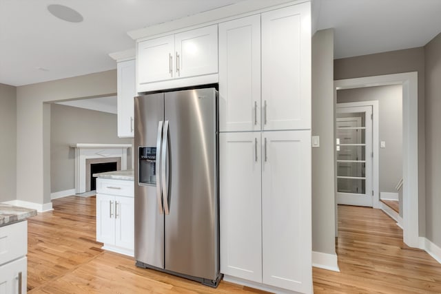 kitchen featuring white cabinetry, stainless steel refrigerator with ice dispenser, light stone counters, and light hardwood / wood-style floors