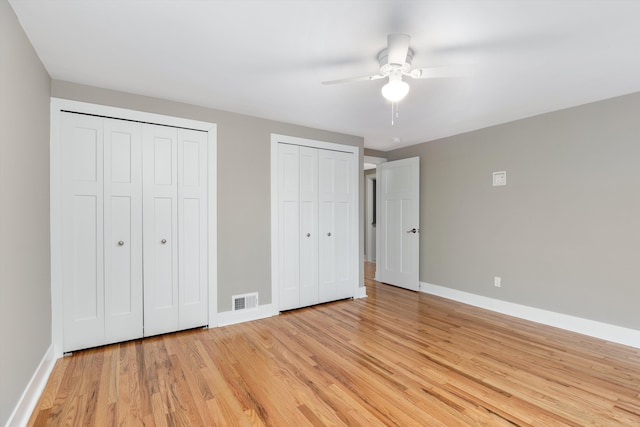 unfurnished bedroom with multiple closets, ceiling fan, and light hardwood / wood-style floors