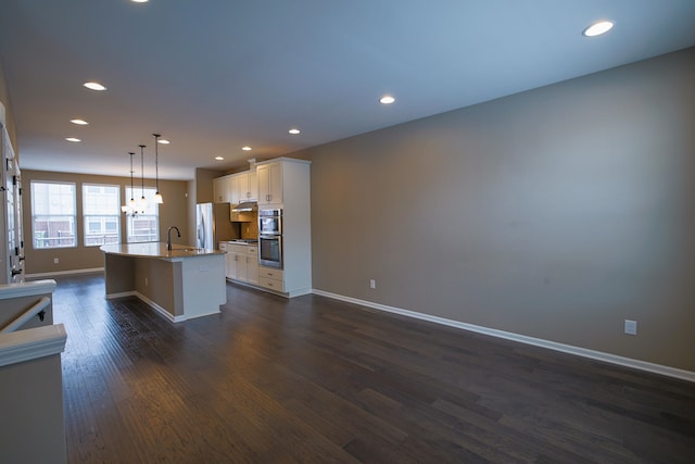 kitchen featuring pendant lighting, sink, a kitchen island with sink, stainless steel appliances, and white cabinets