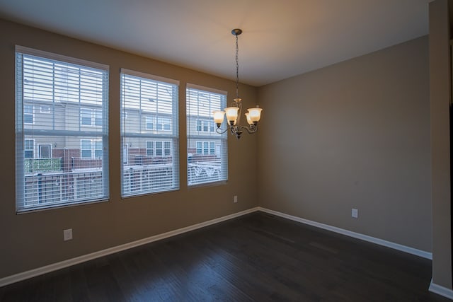 empty room with a notable chandelier and dark hardwood / wood-style flooring