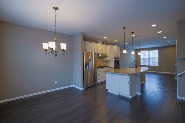 kitchen featuring appliances with stainless steel finishes, a kitchen island with sink, hanging light fixtures, and white cabinets