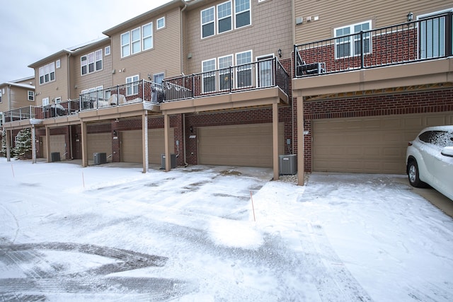 snow covered house featuring a garage and cooling unit