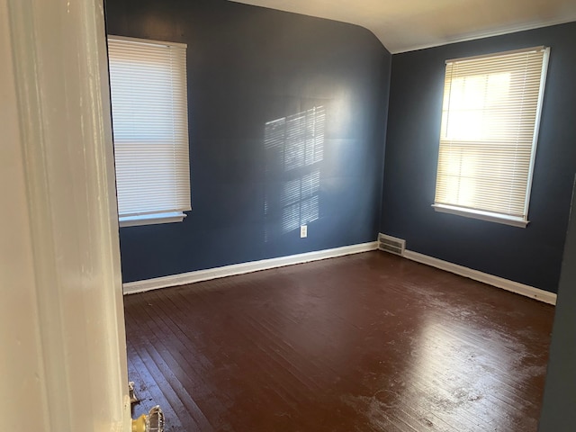 spare room with dark wood-type flooring and lofted ceiling