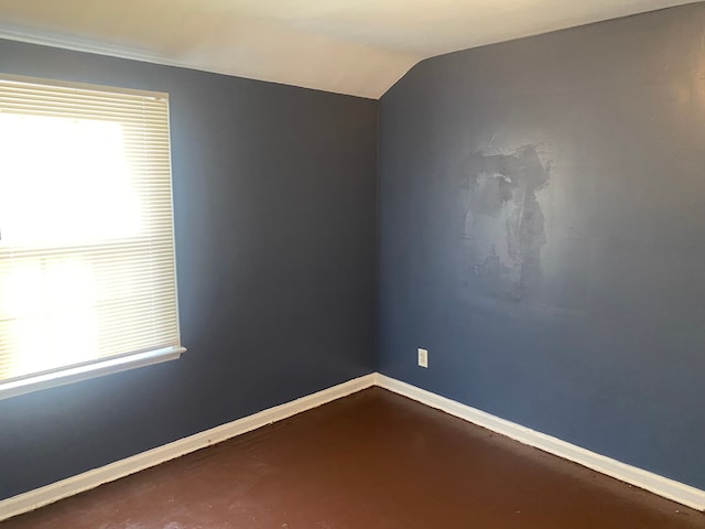 unfurnished room with lofted ceiling and concrete floors