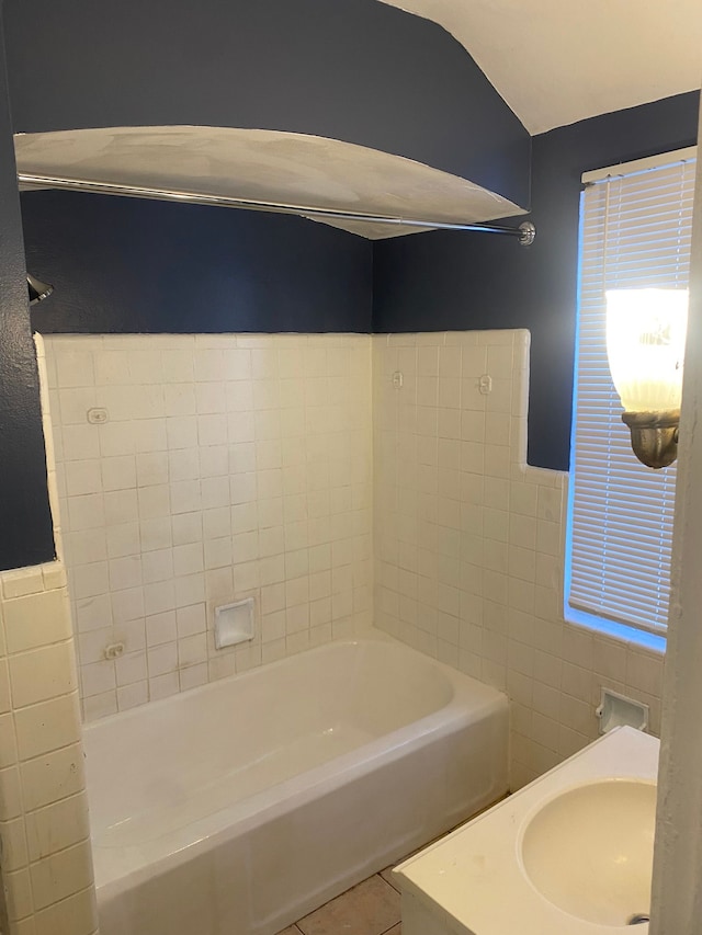 bathroom with tile patterned flooring, sink, tile walls, and a tub to relax in