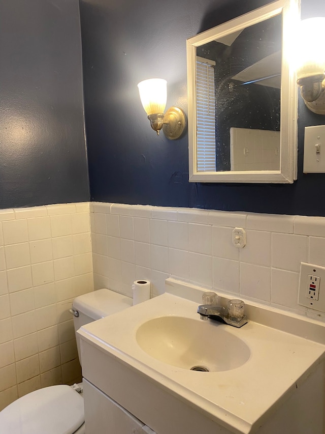 bathroom featuring vanity, toilet, and tile walls