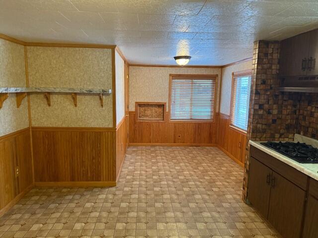kitchen featuring crown molding, wooden walls, and black gas stovetop