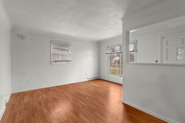 unfurnished room with a textured ceiling and light wood-type flooring