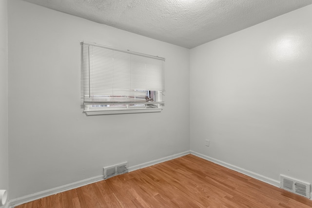 empty room featuring wood-type flooring and a textured ceiling