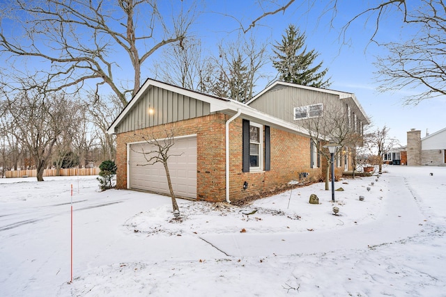 snow covered property with a garage