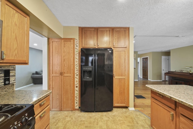 kitchen with black fridge with ice dispenser, light stone countertops, decorative backsplash, and a textured ceiling