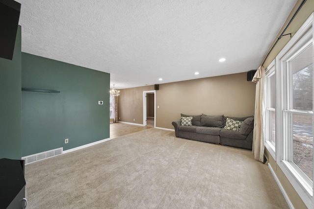 carpeted living room featuring a textured ceiling and a notable chandelier