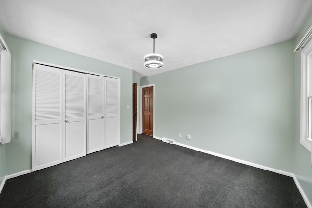 unfurnished bedroom with dark carpet and a closet