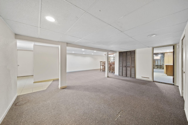 basement with a paneled ceiling and carpet floors