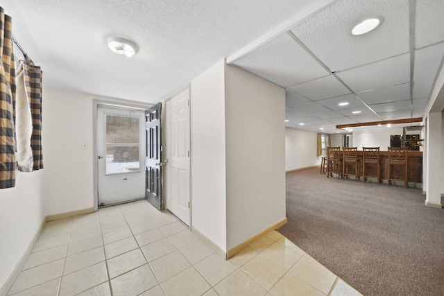 corridor featuring light carpet and a drop ceiling