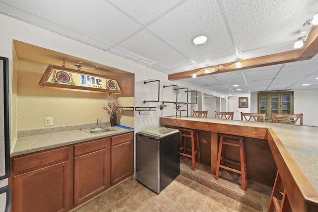 kitchen featuring sink, a paneled ceiling, stainless steel fridge, and kitchen peninsula