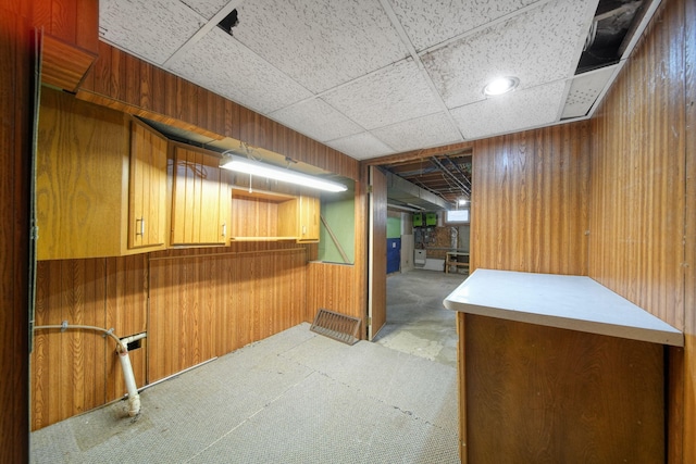 basement with a paneled ceiling and wooden walls