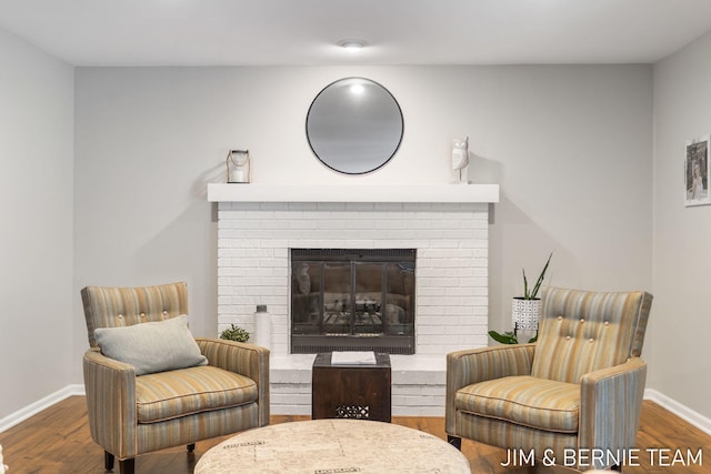 living area with a brick fireplace and dark wood-type flooring