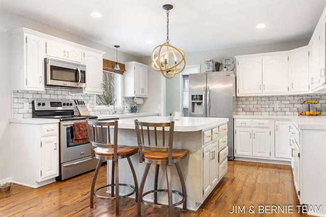 kitchen with pendant lighting, a breakfast bar area, stainless steel appliances, white cabinets, and a kitchen island