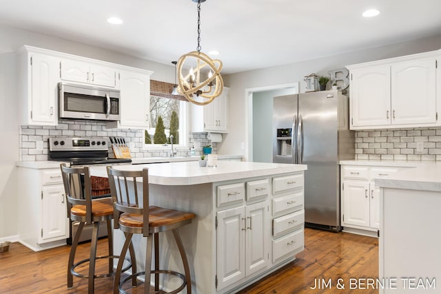 kitchen featuring white cabinetry, appliances with stainless steel finishes, a center island, and dark hardwood / wood-style floors