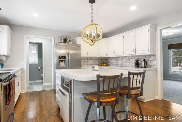 kitchen featuring stainless steel appliances, tasteful backsplash, hanging light fixtures, and white cabinets