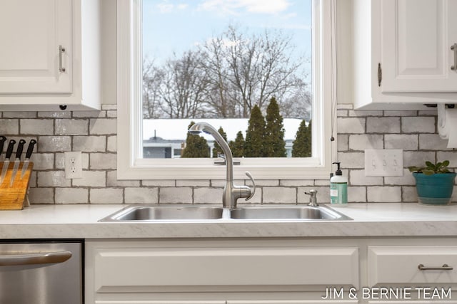 kitchen with backsplash, stainless steel dishwasher, sink, and white cabinets