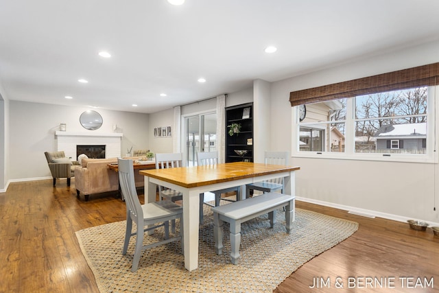 dining area with wood-type flooring and a fireplace