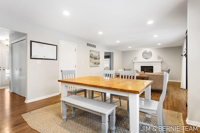 dining area featuring a brick fireplace and dark hardwood / wood-style flooring