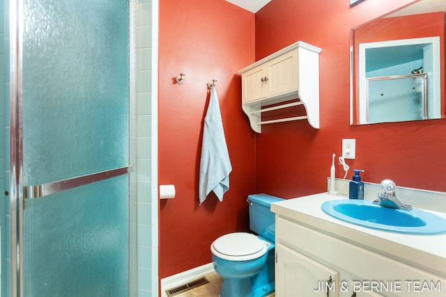 bathroom featuring vanity, a shower with shower door, and toilet