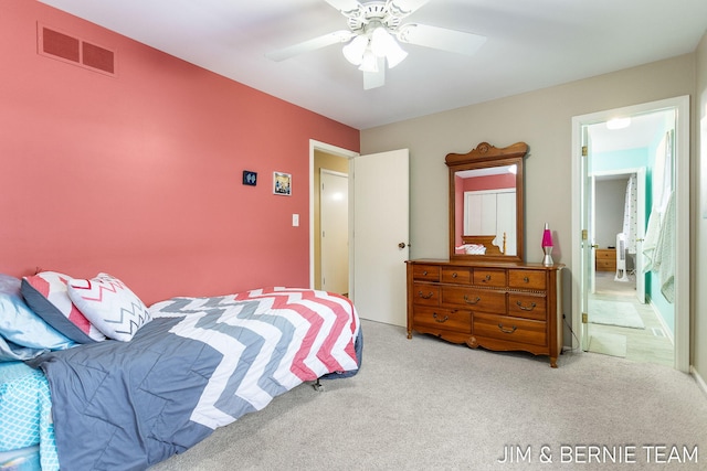 bedroom featuring ensuite bath, light colored carpet, and ceiling fan