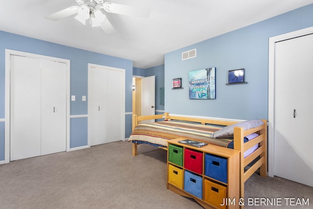 carpeted bedroom with ceiling fan and two closets