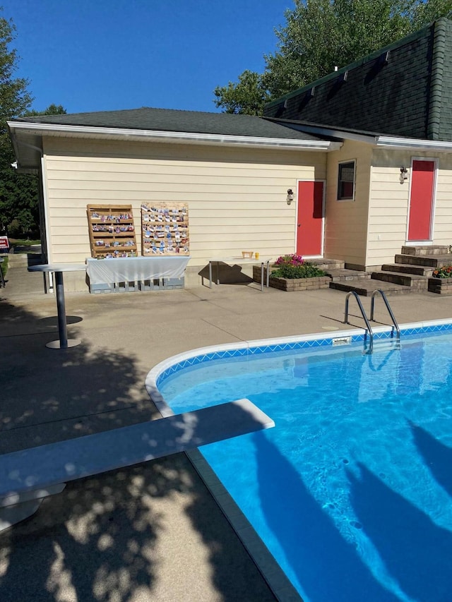 view of swimming pool featuring a patio area and a diving board