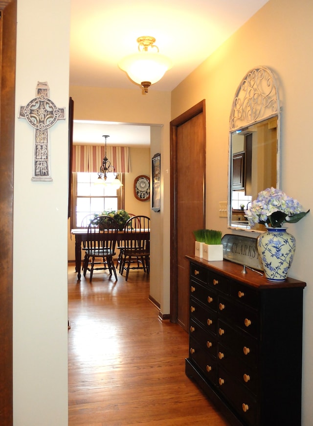 corridor featuring hardwood / wood-style floors and a notable chandelier