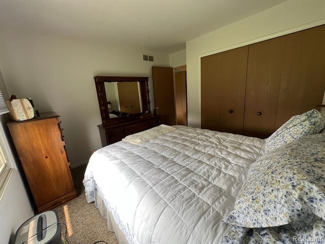 carpeted bedroom with visible vents and a closet