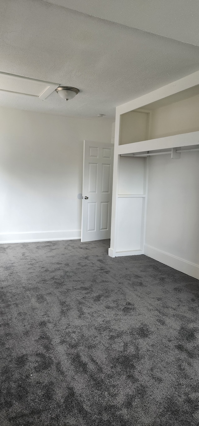 unfurnished bedroom featuring dark carpet and a textured ceiling