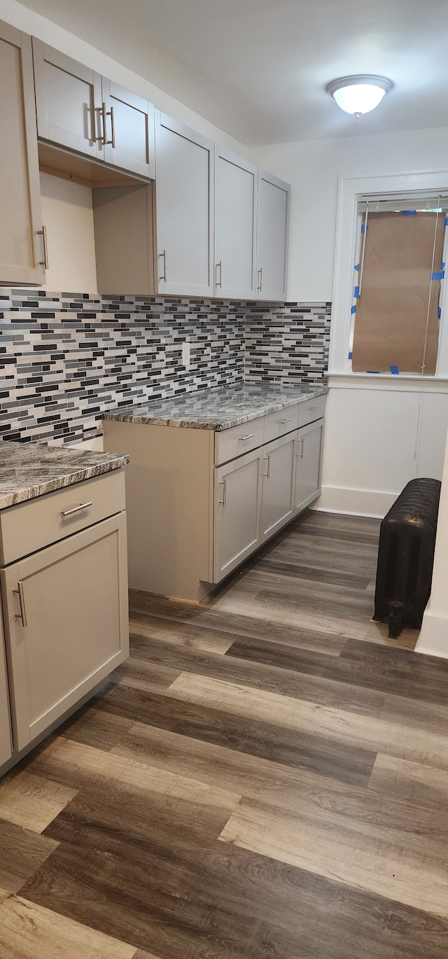 kitchen with tasteful backsplash, light stone countertops, and dark wood-type flooring