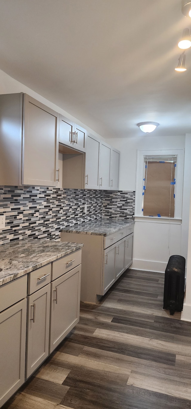 kitchen with stone counters, dark hardwood / wood-style floors, gray cabinetry, and backsplash