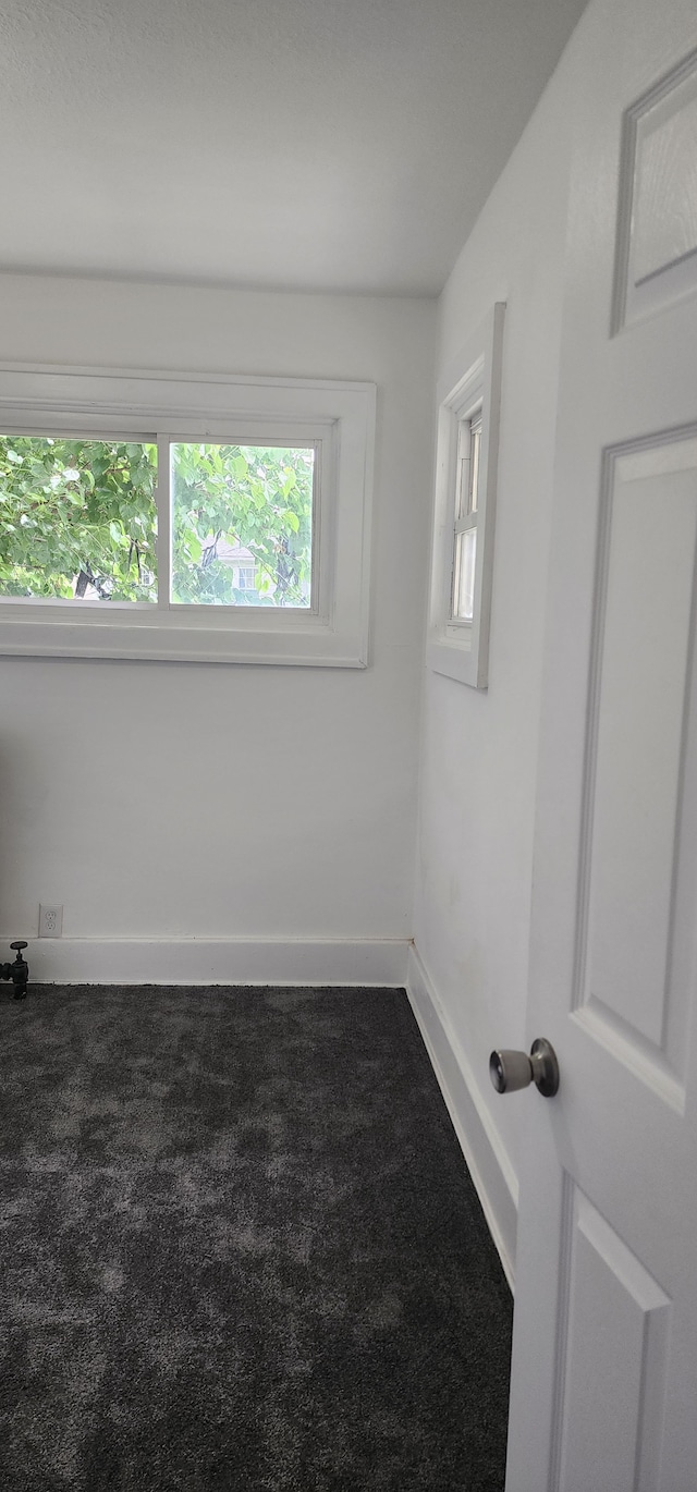 unfurnished room with dark colored carpet