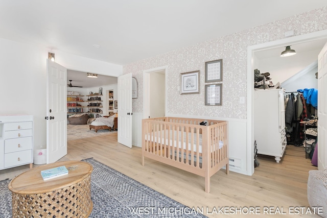 bedroom featuring a walk in closet and light hardwood / wood-style flooring