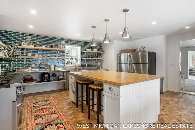 kitchen featuring stainless steel fridge, butcher block counters, a center island, white cabinets, and decorative backsplash