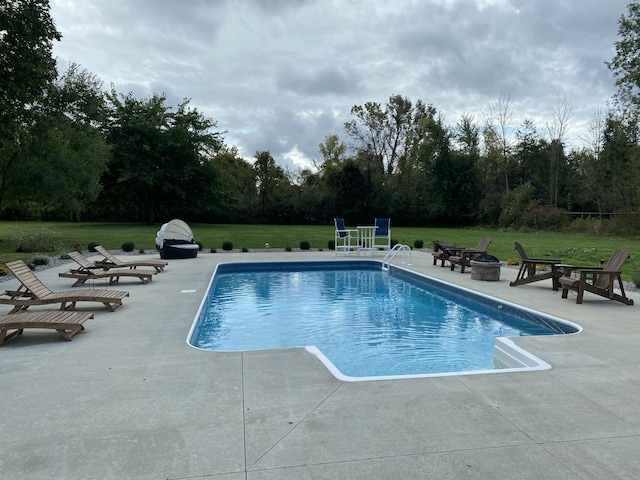 view of pool with a patio, a lawn, and an outdoor fire pit