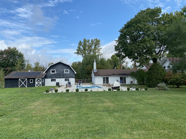 back of property featuring an outdoor structure, a yard, and a patio area