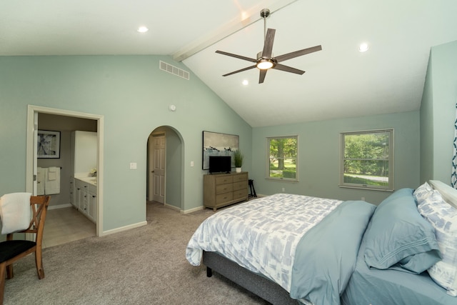 carpeted bedroom with connected bathroom, lofted ceiling with beams, and ceiling fan