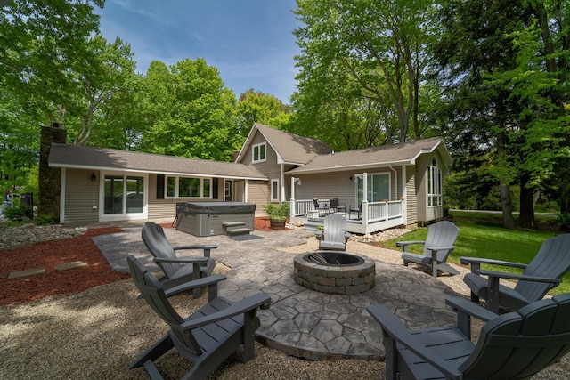 back of house with a wooden deck, an outdoor fire pit, a hot tub, and a patio area