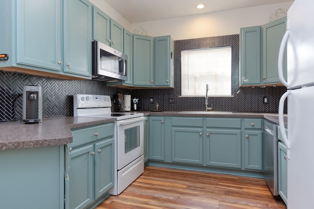 kitchen with sink, blue cabinetry, appliances with stainless steel finishes, tasteful backsplash, and light wood-type flooring