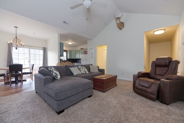 living room featuring ceiling fan with notable chandelier, carpet floors, and high vaulted ceiling