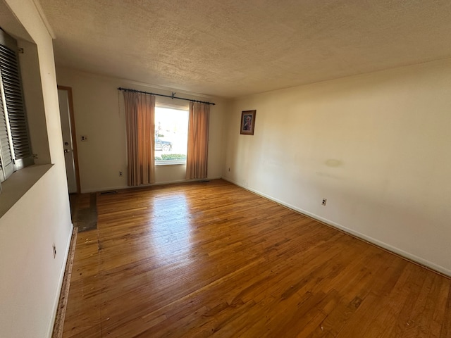 unfurnished room with hardwood / wood-style flooring and a textured ceiling