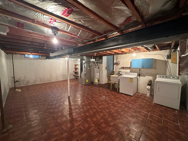 basement featuring heating unit, water heater, sink, dark parquet flooring, and washing machine and dryer